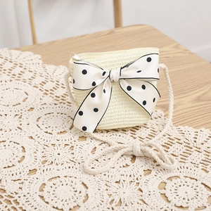 Close-up of cream straw mini bag with large black polka dot silk bow and metal zipper