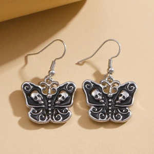 Close-up of gothic butterfly earrings featuring silver metal and black skull relief