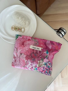 Detailed close-up of colorful floral makeup bag with simple wish label and metal zipper
