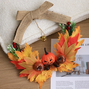 Autumn pumpkin and maple leaf wreath with burlap bow and gold bells on a white faux fur rug