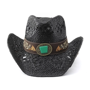 Detailed view of black woven cowboy hat with gold flower embroidery and green gemstone