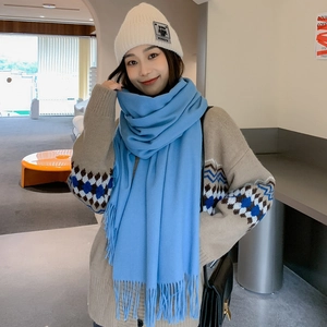 Detail of blue wool cashmere scarf with fringe paired with a beige knit beanie hat