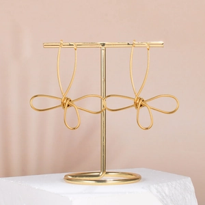Minimalist gold abstract flower hoop earrings on a display stand with rock base