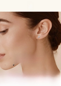Close-up of elegant moissanite stud earrings in a leaf shape on a model ear
