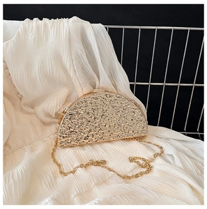 Detail of semicircular evening bag with gold textured metallic finish and chain strap