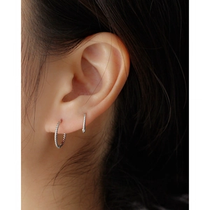 Close-up of elegant S925 sterling silver twisted hoop earrings worn on a female ear