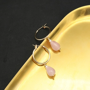 Elegant gold drop earrings with pink crystal and white pearl on a metal tray
