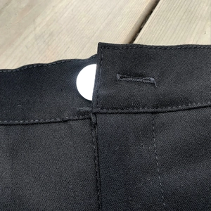 Dettaglio di pantaloncini neri a vita alta con bottone bianco e trama in tessuto resistente