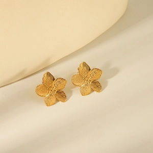 Golden titanium steel flower stud earrings with intricate petal texture on beige background