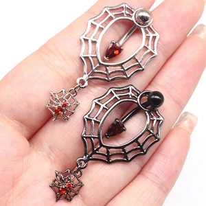 Detail of spider web navel rings in silver and black finish with red teardrop stones