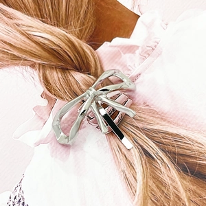 Close-up of a silver bow-shaped metal hair clip styled on elegant blonde hair