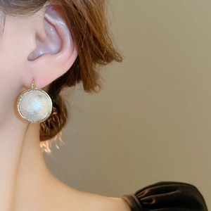 Gros plan de boucles d'oreilles créoles perles baroques dorées sur le mannequin