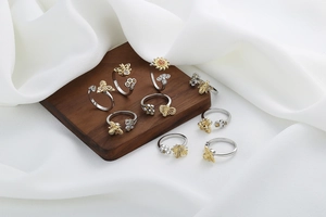 Detail of bee and honeycomb rings set with cubic zirconia on wood and silk