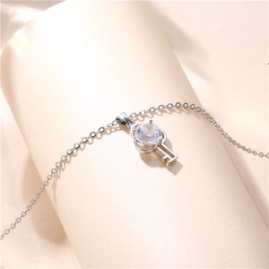 Silver stainless steel necklace with a zircon-inlaid key pendant on a soft beige background
