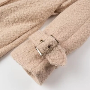 Detailed close-up of beige lamb wool coat cuff with stylish square metal buckle detail