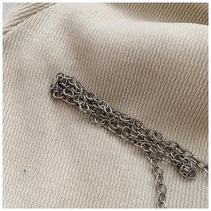 Close-up of polished silver metal chain strap on beige ribbed fabric texture