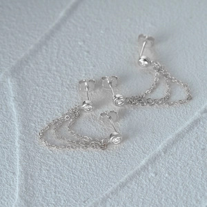Close-up of s925 silver star tassel earrings with chains on a textured white background