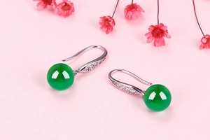 Close-up of chalcedony drop earrings with silver hooks and sparkling zircon accents