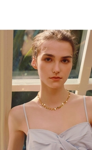 Close-up of golden sequin choker necklace featuring layered metallic round disc pendants
