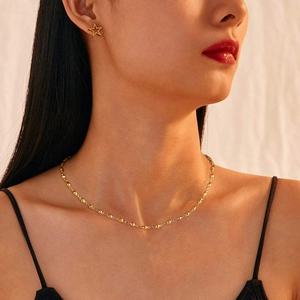 Close-up of golden stainless steel star earring and beaded necklace on a model