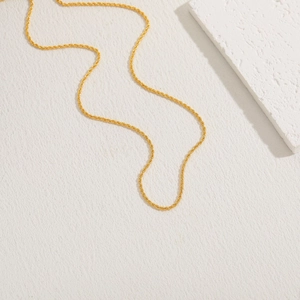 Detail of 18K gold-plated minimalist rope chain necklace on white textured background