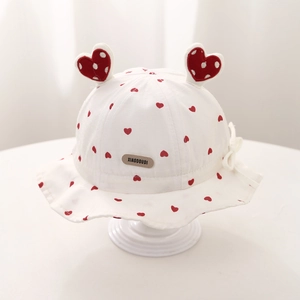 Détail d'un chapeau de soleil bébé avec motifs cœurs, oreilles Mickey et nœud blanc
