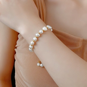 Detailed close-up of a baroque pearl bracelet with gold beads on a woman's wrist