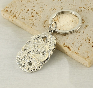Close-up of a silver stainless steel keychain featuring a detailed Chinese dragon carving