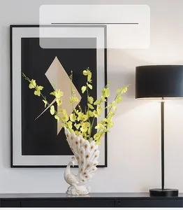 Detailed view of elegant white peacock vase with golden accents and yellow dancing orchids