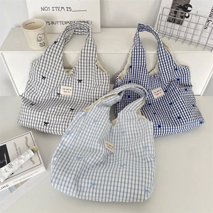Gros plan de sacs cabas en toile à carreaux bleus et noirs avec broderies de fleurs