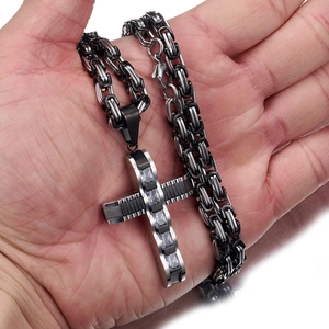 Nahaufnahme von Kreuzanhänger mit Zirkonia und Byzantiner-Kette auf der Handfläche