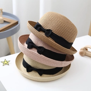 Straw sun hats in brown and beige with wide black ribbons and elegant bow details