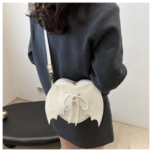 Detail of white heart-shaped crossbody bag with bat wings on a model back view