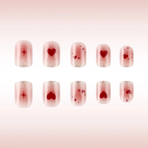 Close-up of pink glitter heart press-on nails with red gradient and star details