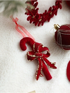 Close-up of red flocked candy cane Christmas pendant with gold glitter and bow