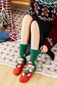 Close-up of fluffy green and red Christmas coral fleece socks with warm holiday embroidery