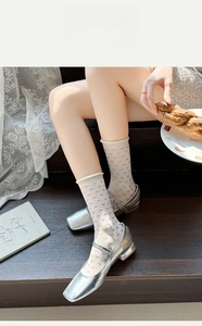 Dettaglio di calzini in rete bianca con cuori e scarpe Mary Jane argento a punta quadra