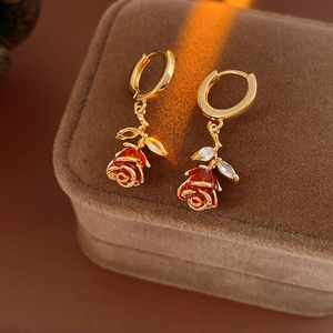 Vue macro de boucles d'oreilles rose émaillée rouge et zircons sur boîte en velours