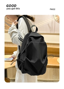 Side view of a black pleated nylon backpack with drawstring pockets on a person