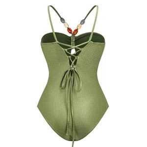 Close-up of grass green textured swimsuit with lace-up back and colorful bead accents