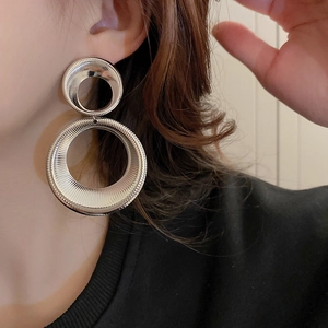 Detail of silver geometric double ring earrings with radial texture on female model