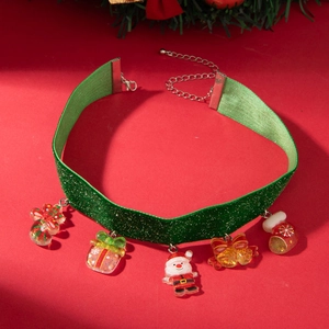 Detail of green velvet Christmas choker with festive charms on a red background