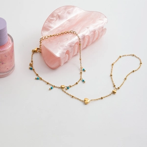 Close-up of 18K gold stainless steel heart bracelet with blue beads on marble accessory