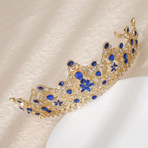 Detail of gold crown with blue gems and crystals featuring floral and leaf patterns
