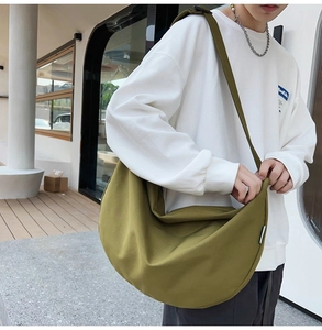 Olive green large oxford crossbody bag worn by a model in an outdoor urban setting