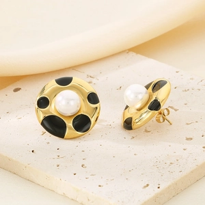 Detailed macro shot of vintage gold stud earrings with black enamel and central pearl inlay