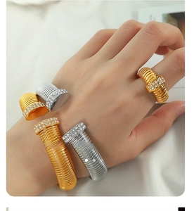 Detailed view of women wearing silver and gold coiled metal bracelets with sparkling rhinestones