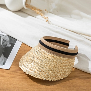 Close-up of straw sun visor hat with woven texture and black beige ribbon detail