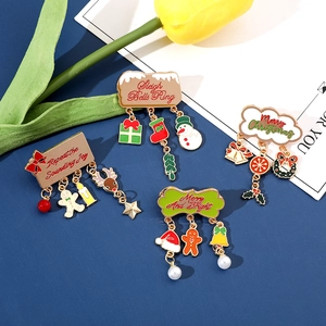 Detail of four festive Christmas metal pins with bells, snowmen and pearl pendants