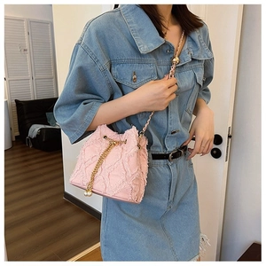 Pink frayed denim bucket bag featuring a gold chain strap and elegant pearl charm detail